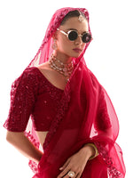 Woman wearing a red embroidered saree with sunglasses and jewelry on a white background