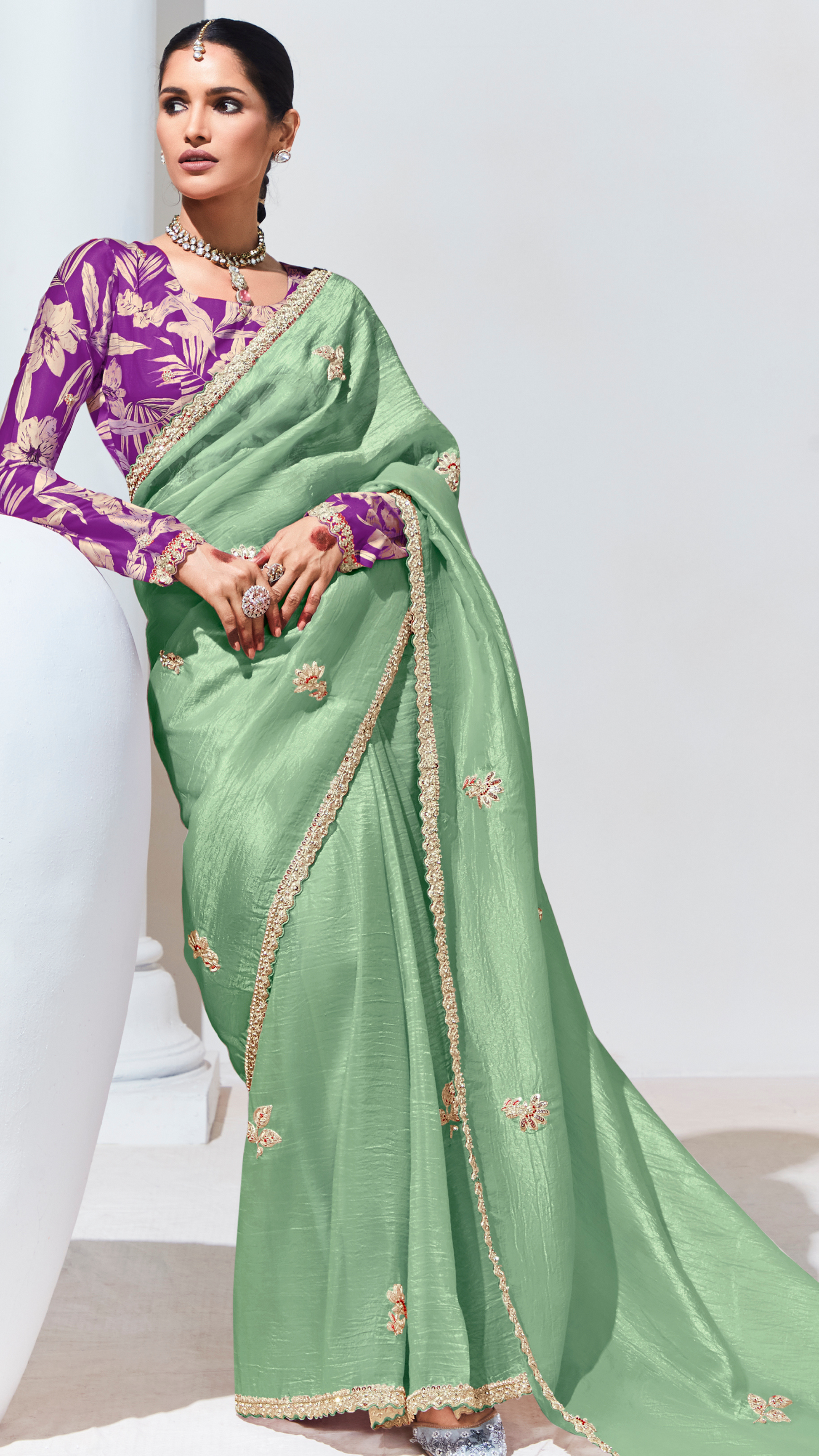 Green saree with gold border worn by a person on a white background