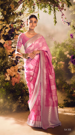 Woman in a pink saree standing among flowers and greenery