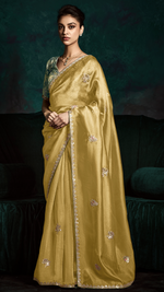Woman wearing a traditional yellow saree with a dark background