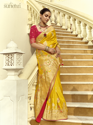 Woman in a yellow saree with pink blouse standing on a staircase