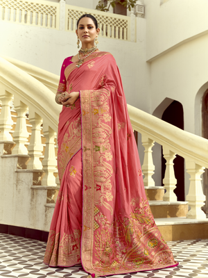 Woman wearing a pink saree with intricate designs in an elegant indoor setting.