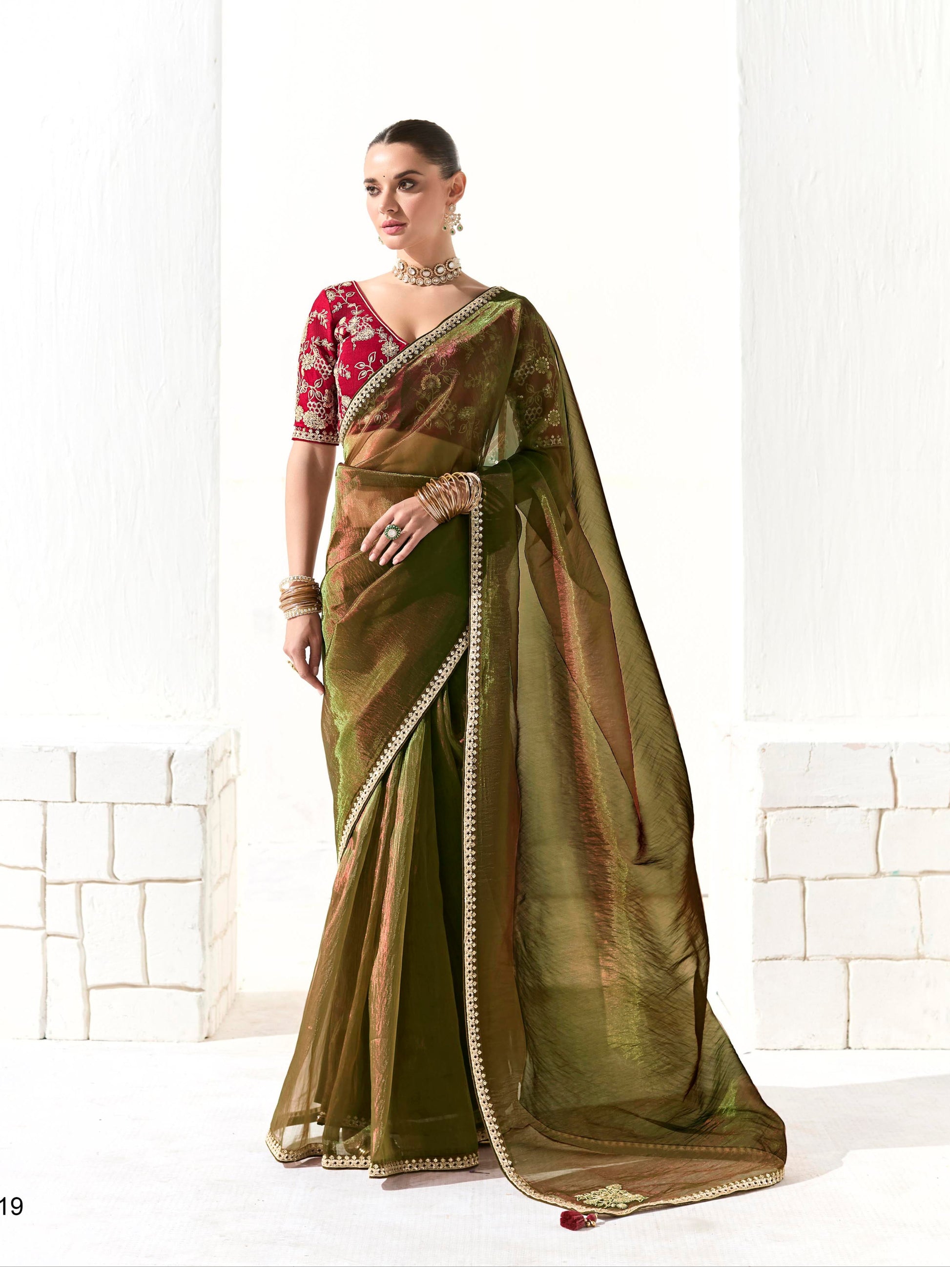 Woman wearing a green saree with a red blouse against a white background, branded 'Kimora'.