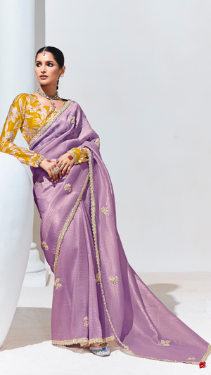 Woman wearing a purple saree with gold embroidery on a white background