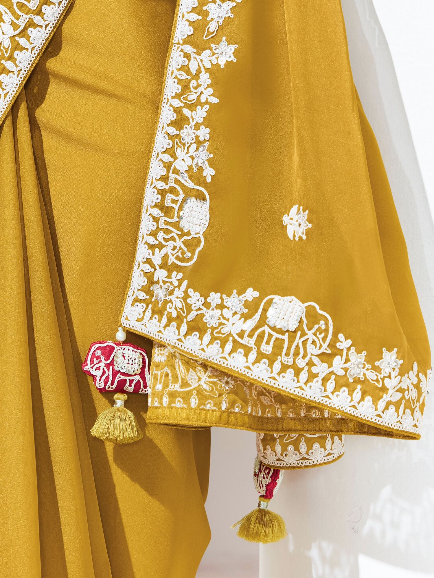 Mustard yellow traditional outfit with white embroidery on a plain background