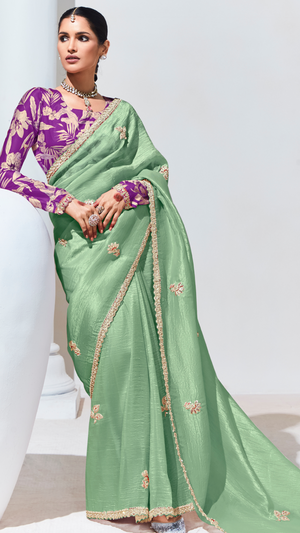 Green saree with gold border worn by a person on a white background