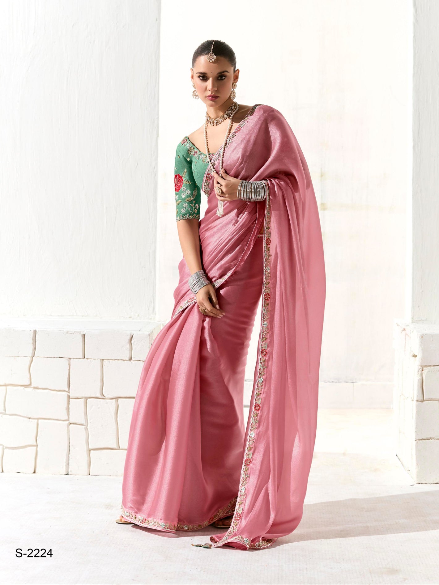 Woman wearing a pink saree with a white background, featuring the brand 'kimora'.