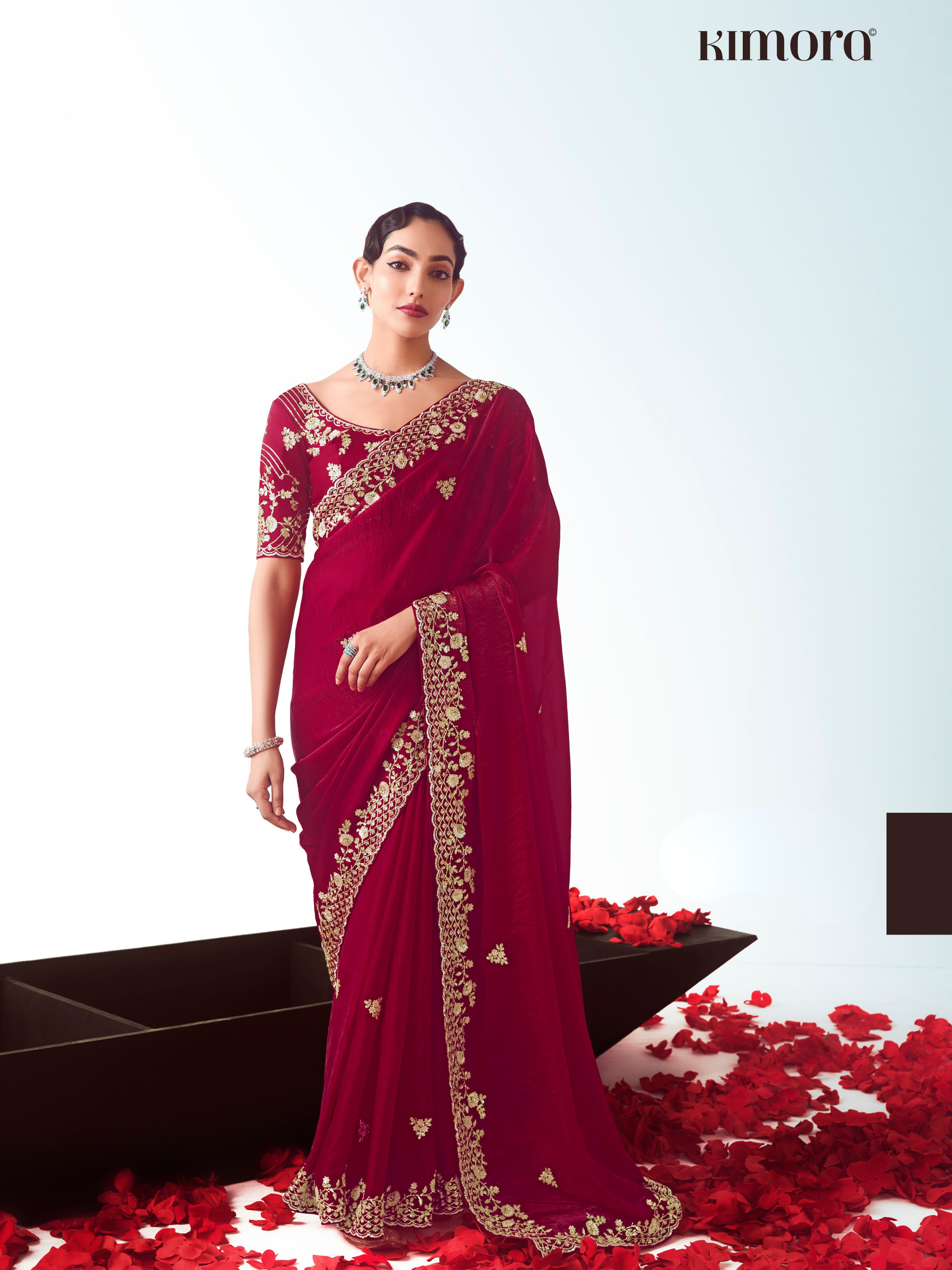 Woman wearing a red saree with gold embroidery on a white background