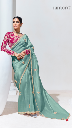 Woman wearing a teal saree with pink blouse on a white background