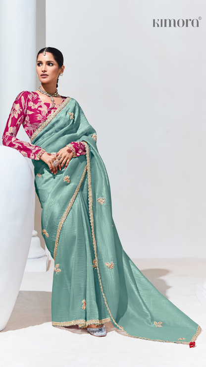 Woman wearing a teal saree with pink blouse on a white background