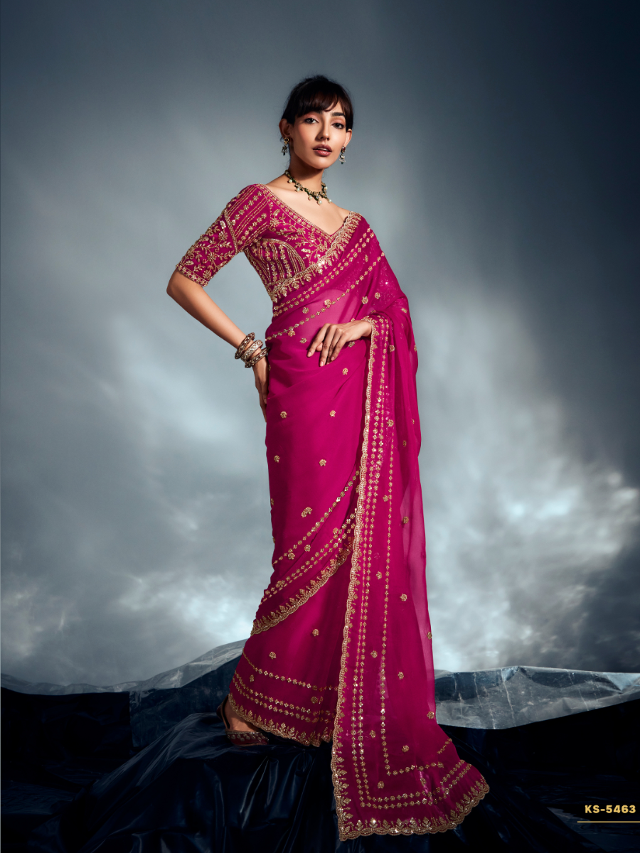 Woman wearing a pink saree with gold embroidery against a dark background