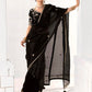 Woman wearing a black saree with gold details against a white background
