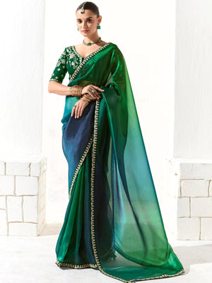 Woman wearing a green and blue saree with a white background