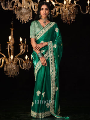 Woman wearing a green saree with white patterns in front of chandeliers