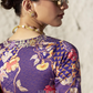 Woman wearing a patterned blouse with floral and geometric designs.