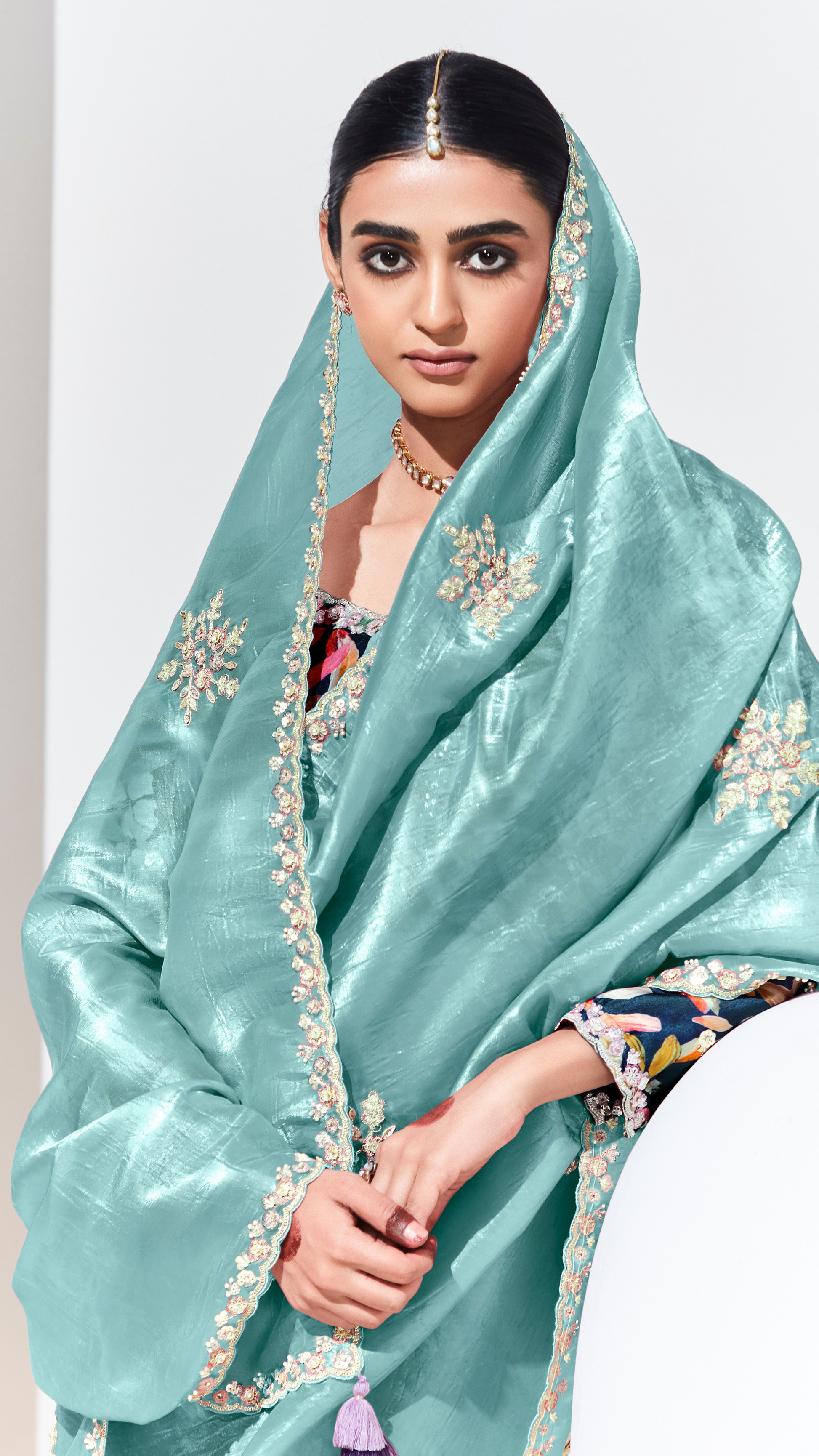 Woman wearing a light blue saree with floral embroidery on a white background