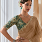 Woman wearing a traditional saree with intricate designs in a well-lit room.