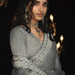 Woman in a traditional outfit with jewelry against a dark background