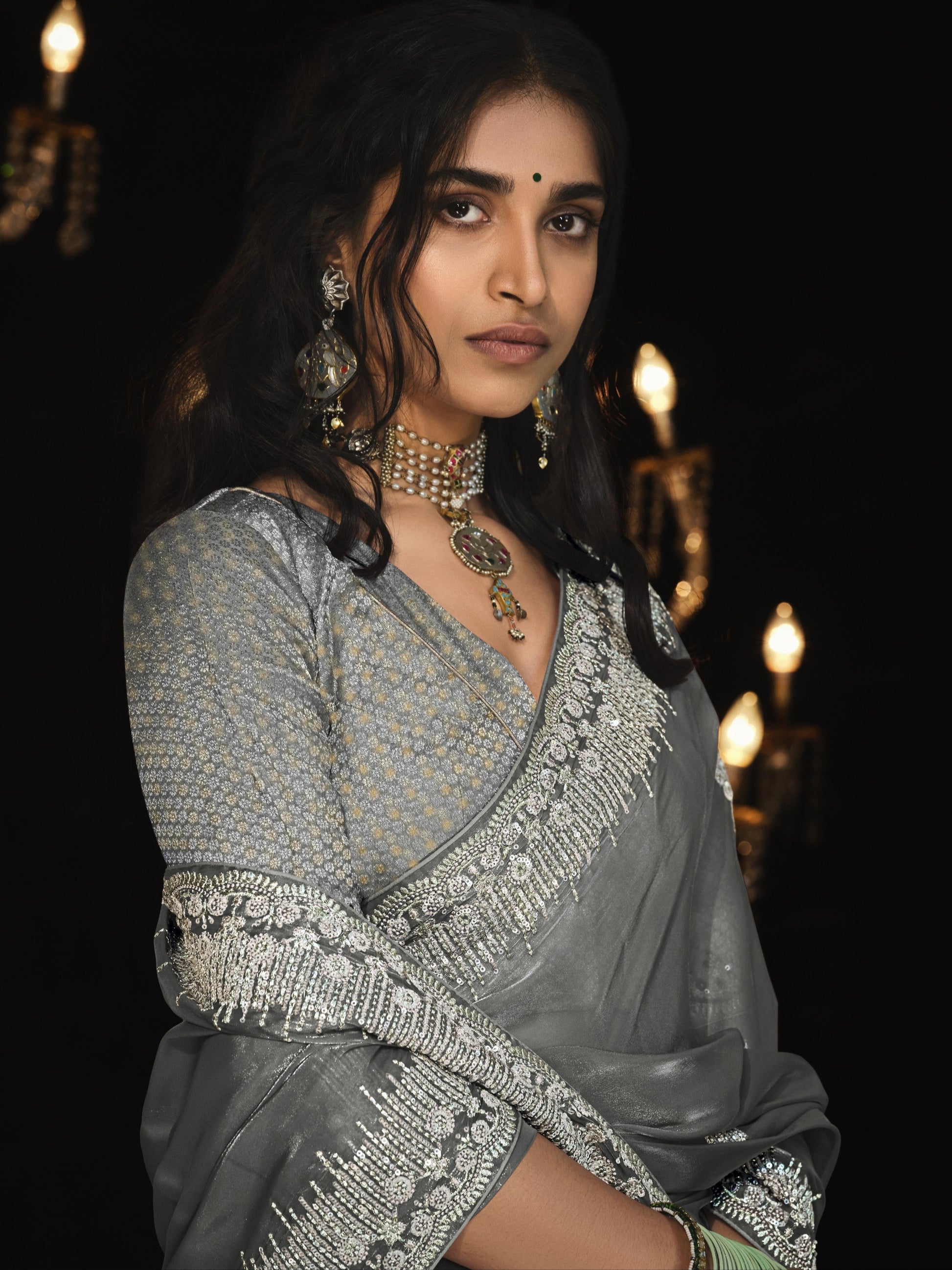 Woman in a traditional outfit with jewelry against a dark background