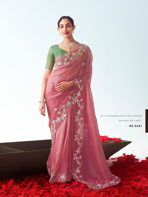 Woman wearing a pink saree with white embroidery on a red carpet