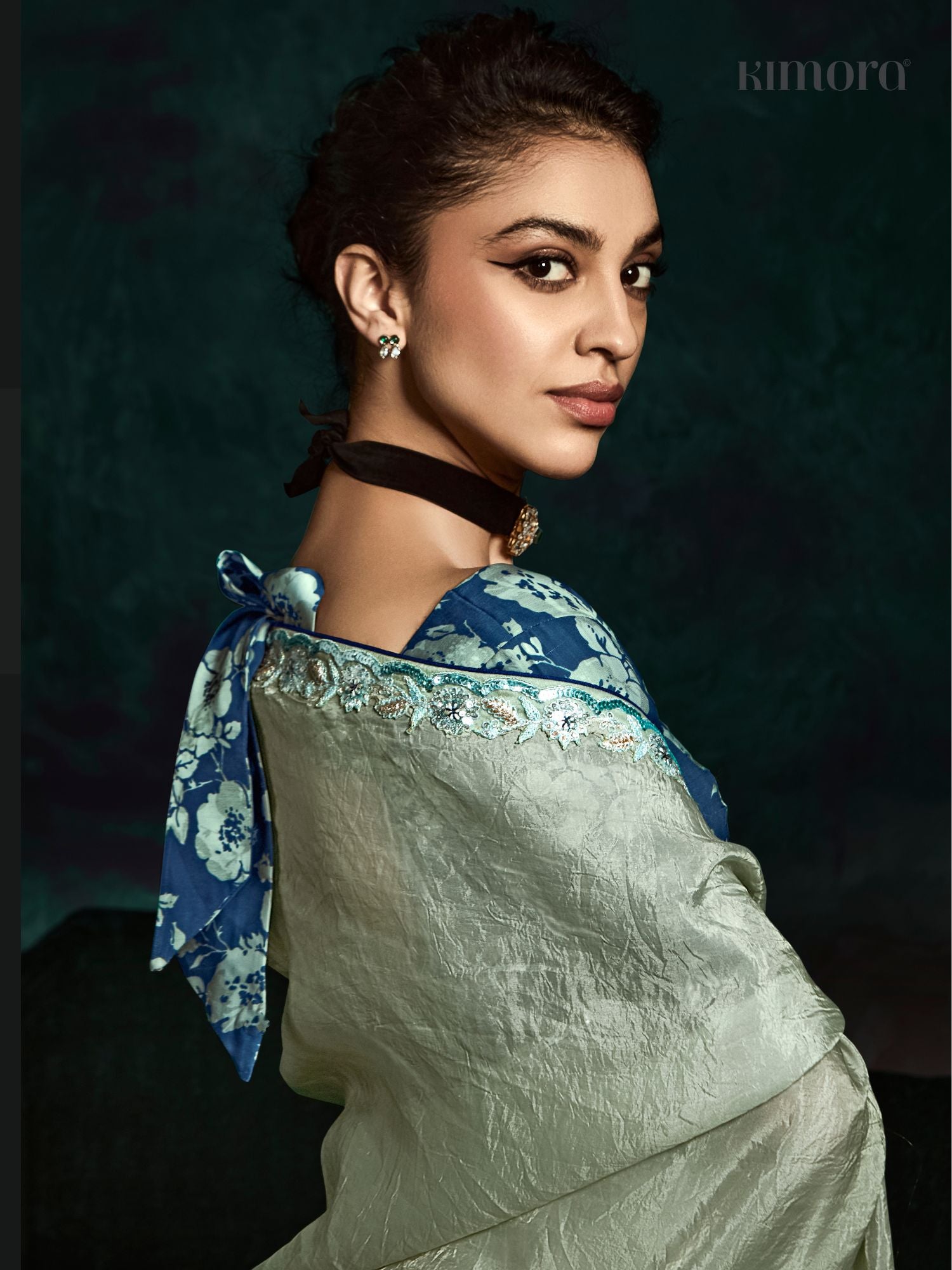 Woman wearing a traditional outfit with a blue and white floral design on a dark background