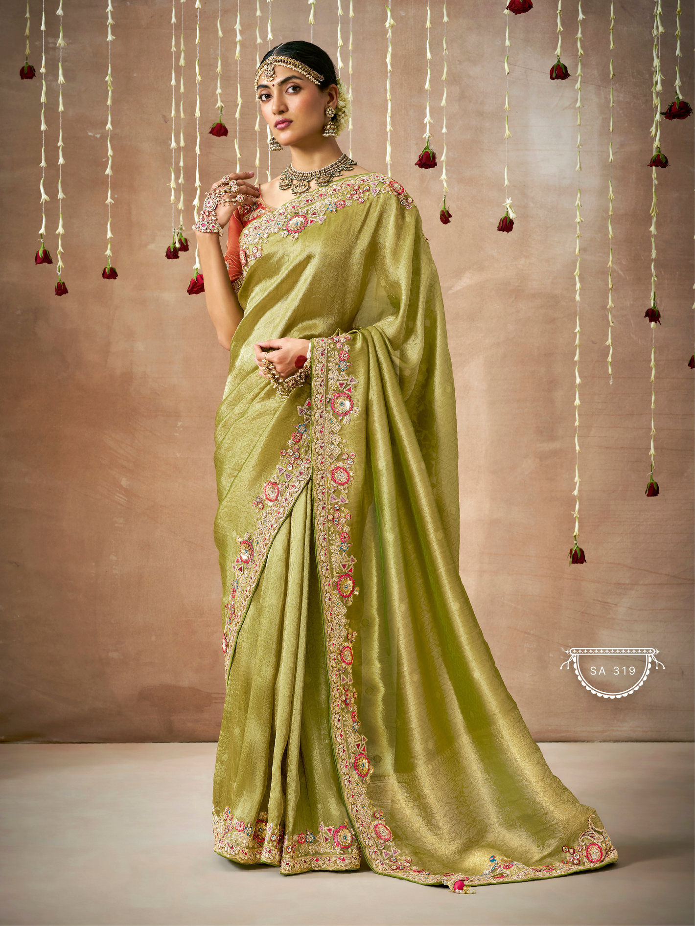 Woman wearing a green saree with floral patterns against a beige background