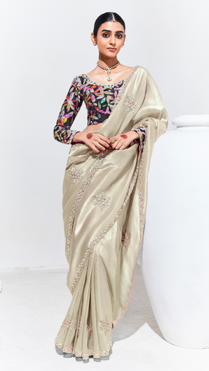 Woman wearing a beige saree with floral blouse on a white background