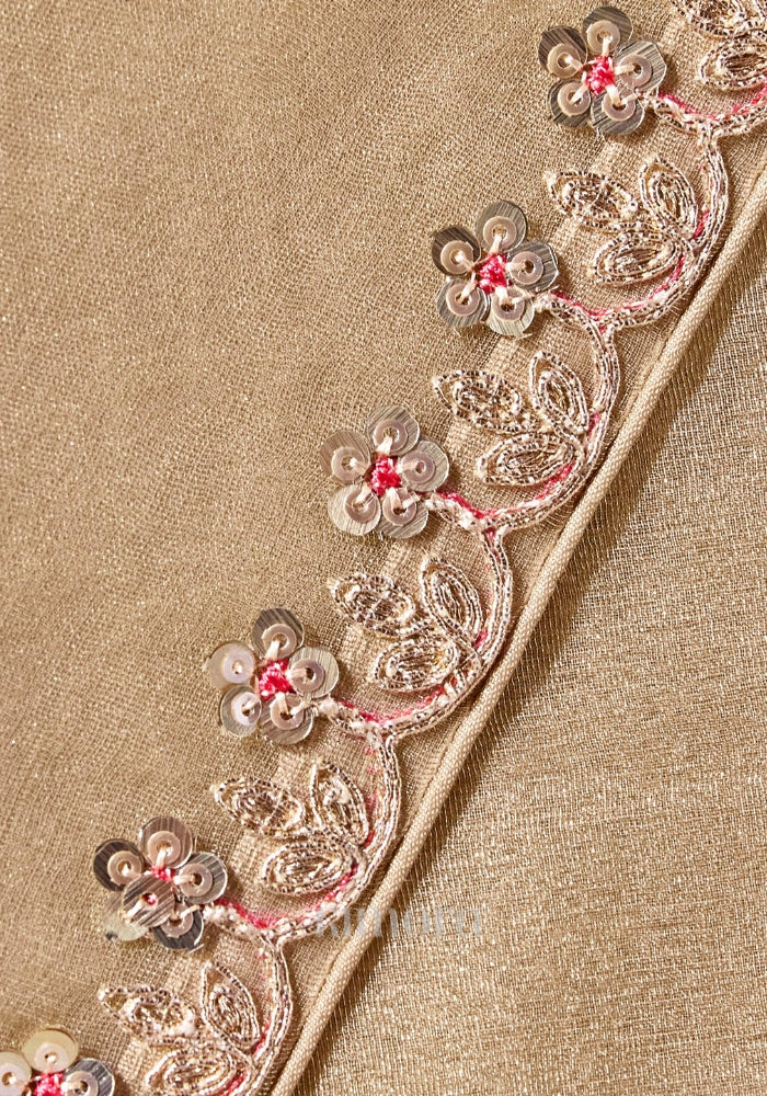 Close-up of the champagne gold saree showcasing intricate zari, sequins and bead embroidered floral border with elegant craftsmanship.