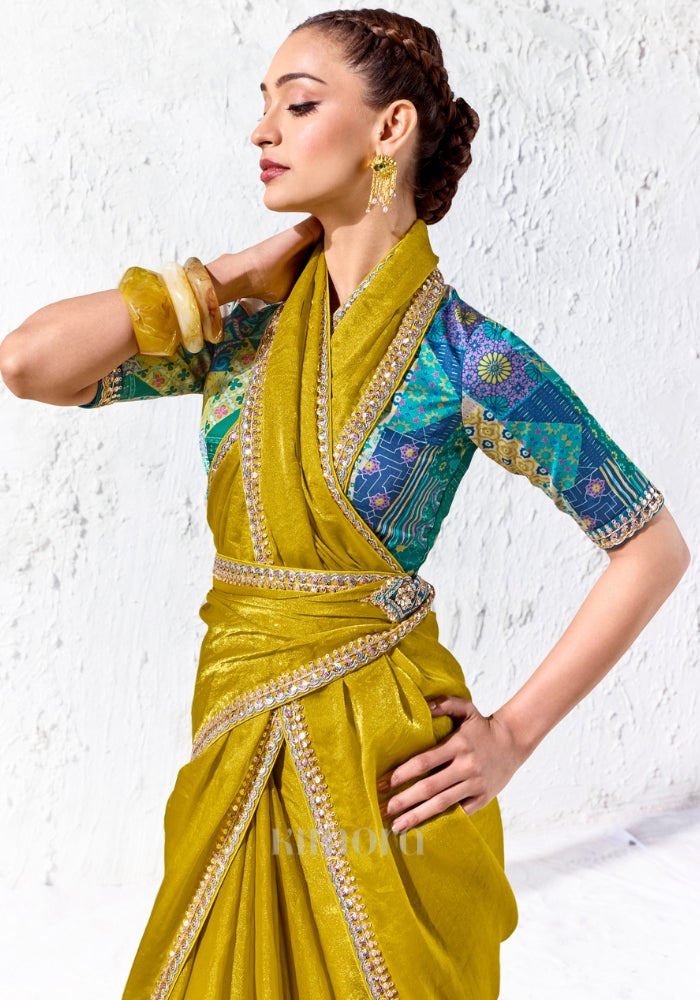 Designer chartreuse yellow tissue silk saree featuring an embroidered border and teal multicolour printed blouse for festive occasions.