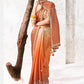 Elegant ombre designer saree in ivory and burnt orange with embroidered border, scattered floral motifs and silk tassels, perfect for weddings and festive celebrations.