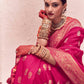Woman in a pink traditional outfit with gold jewelry against a light background