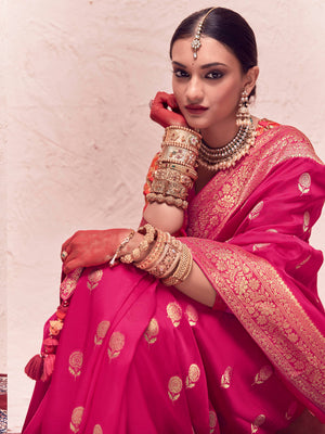Woman in a pink traditional outfit with gold jewelry against a light background