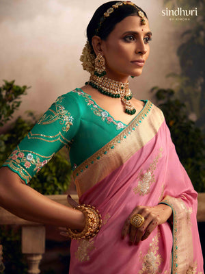 Woman wearing a traditional saree with green blouse and pink dupatta, standing outdoors.