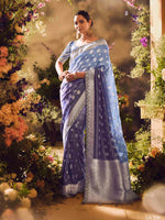 Woman in a blue saree standing in front of a floral archway