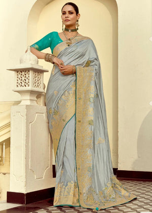 Woman wearing a light blue saree with gold patterns indoors.