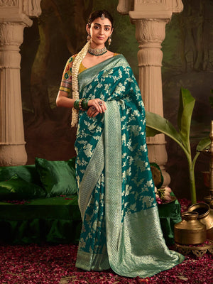 Woman in a green saree with white patterns standing in an ornate setting.