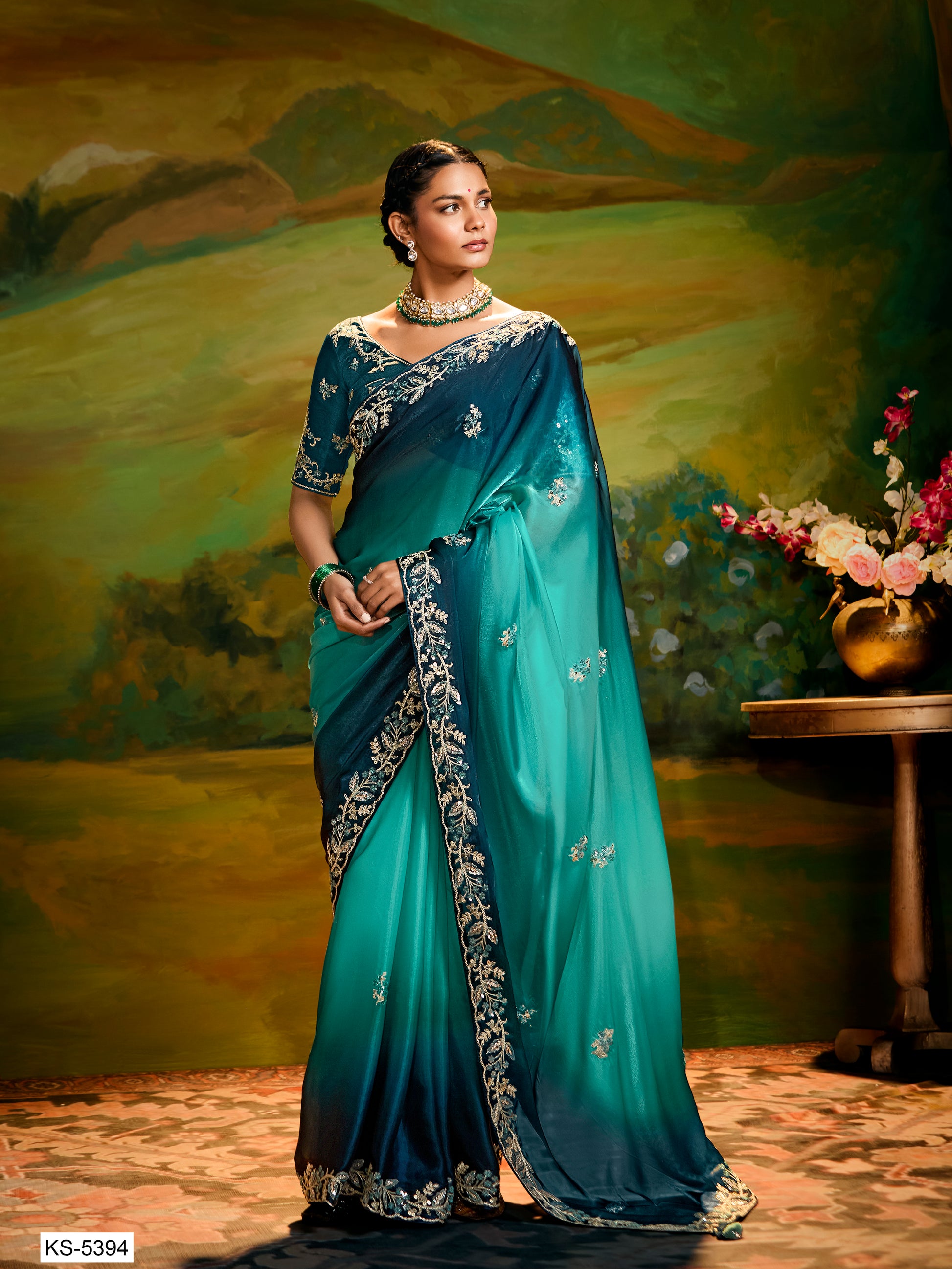 Woman wearing a traditional teal and navy saree with a scenic background