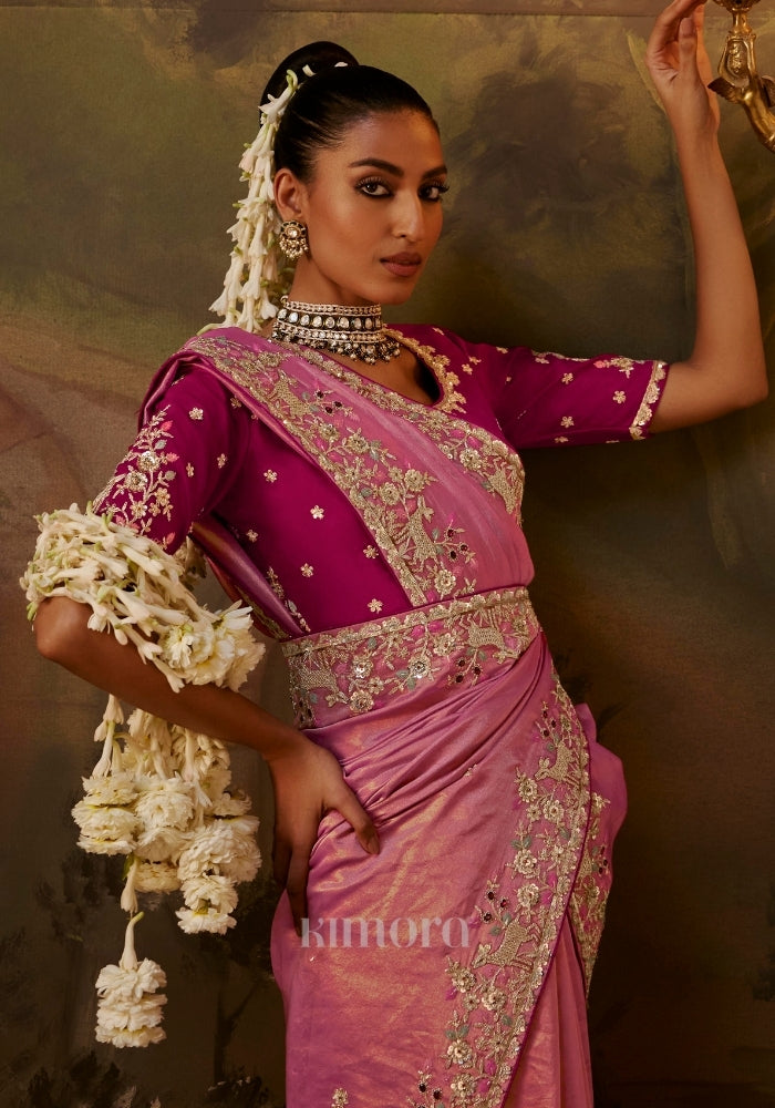 Woman wearing a pink embroidered silk saree with a magenta blouse, traditional 