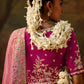 Side view of a woman in a pink silk saree with embroidered border