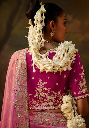 Side view of a woman in a pink silk saree with embroidered border