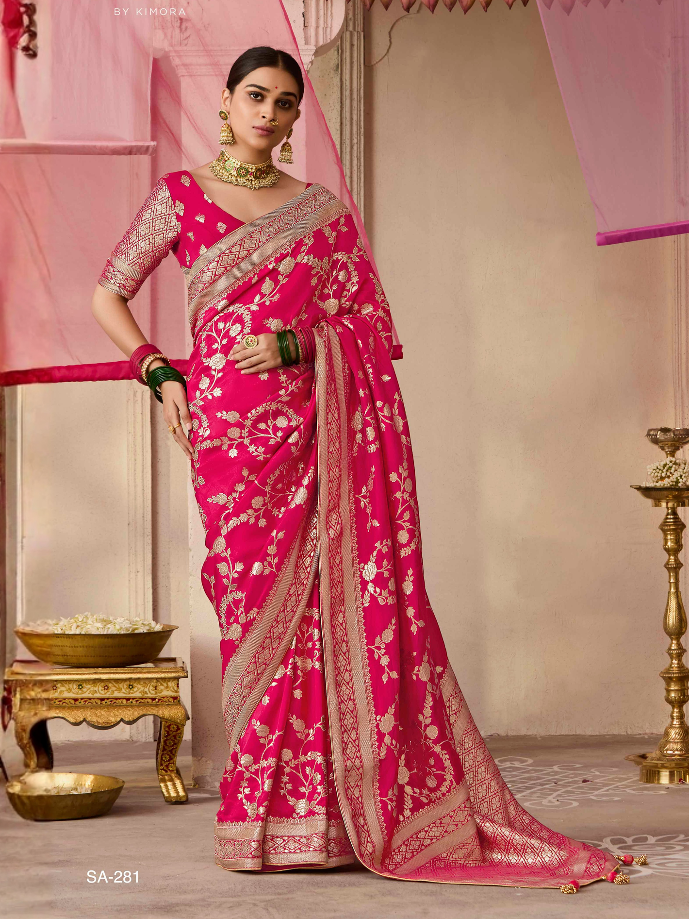 Woman wearing a pink saree with a gold border in an indoor setting