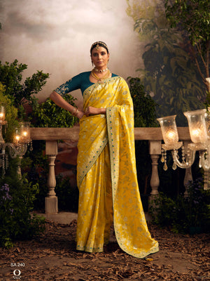 Woman in a yellow saree standing outdoors with decorative elements.