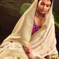 Woman in a white saree with a plant and traditional lamp in the background