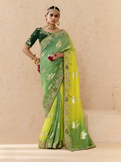 Woman wearing a green and yellow saree with floral patterns on a beige background